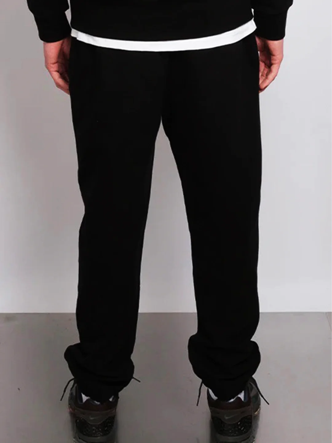 Person wearing black pants with a white waistband on a plain background